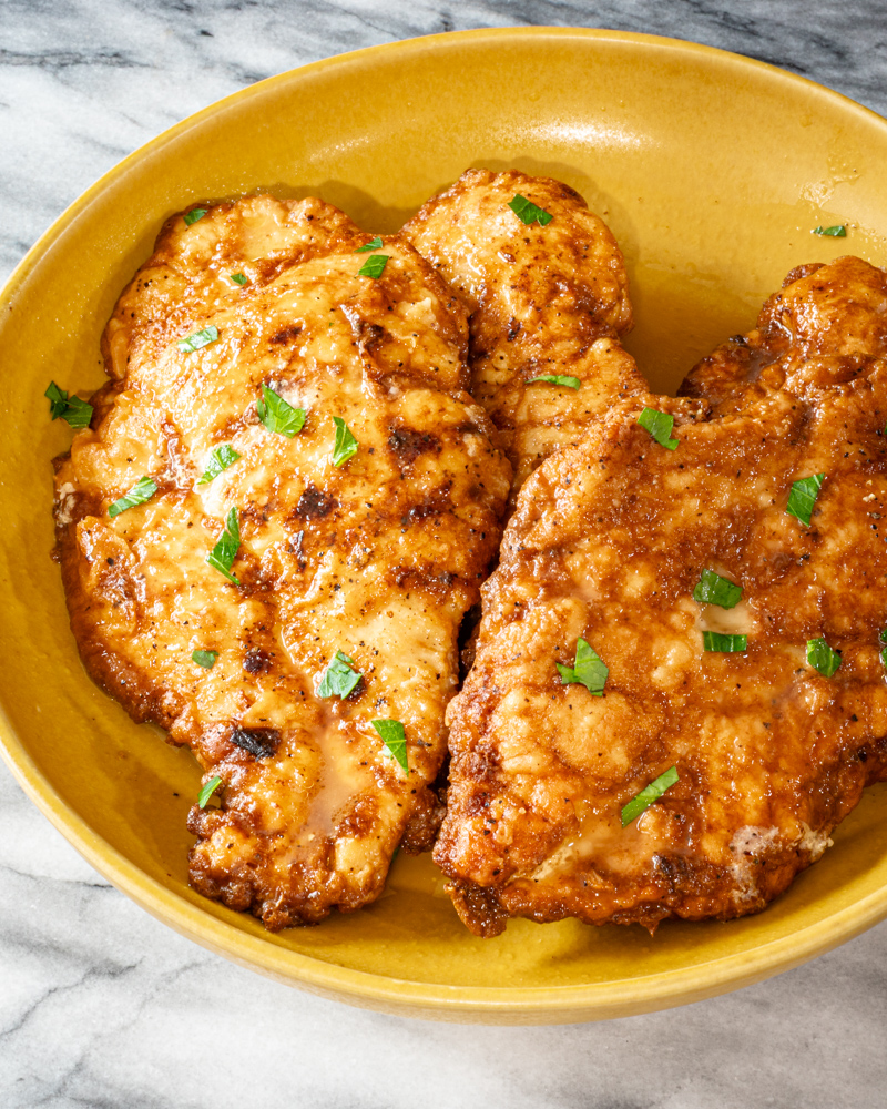 Chicken Francese in a bowl with parsley garnish.