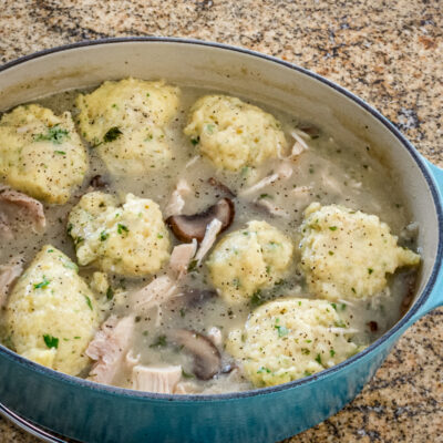 Savory chicken and dumplings simmering in a flavorful broth with mushrooms and herbs.