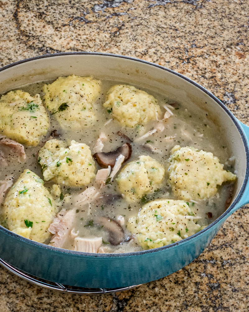 Savory chicken and dumplings simmering in a flavorful broth with mushrooms and herbs.