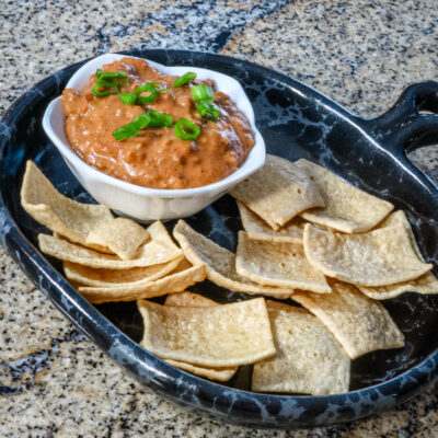 Chili cheese and sausage dip with crackers on a dark plate.