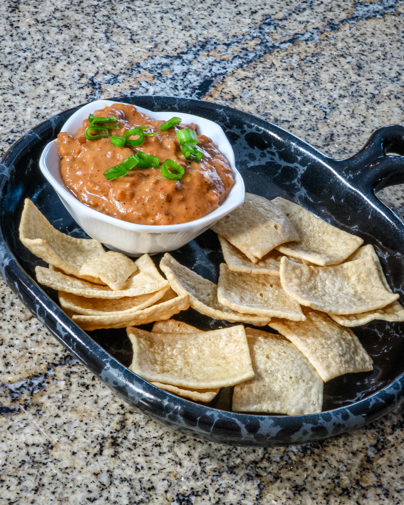 Chili cheese and sausage dip with crackers on a dark plate.