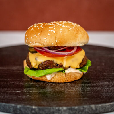 grilled burger with chipotle mayonnaise or aioli on a board with a cheeseburger in the background