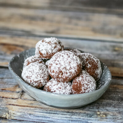 Chocolate butterball cookies stacked in a small dish.