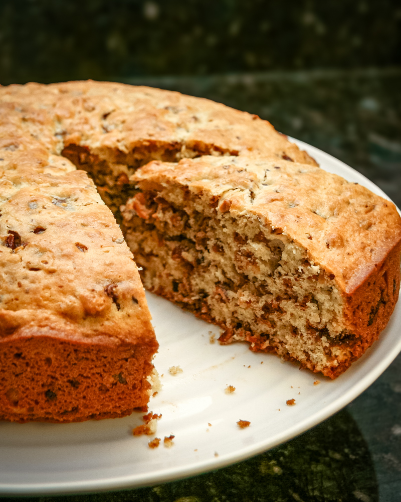 Chocolate chip cake on a light colored cake plate.