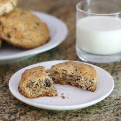 chocolate chip scones on plates with a glass of milk in the background.