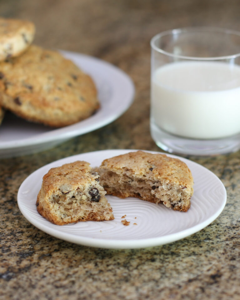 chocolate chip scones on plates with a glass of milk in the background.