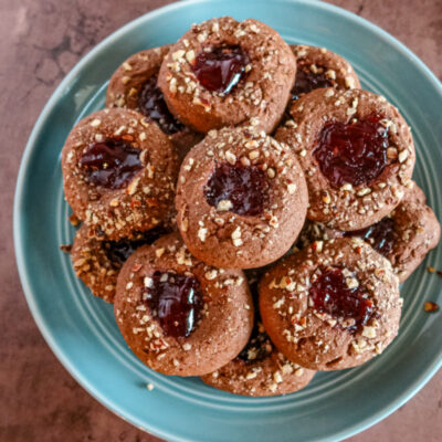 Chocolate raspberry thumbprint cookies on a plate.