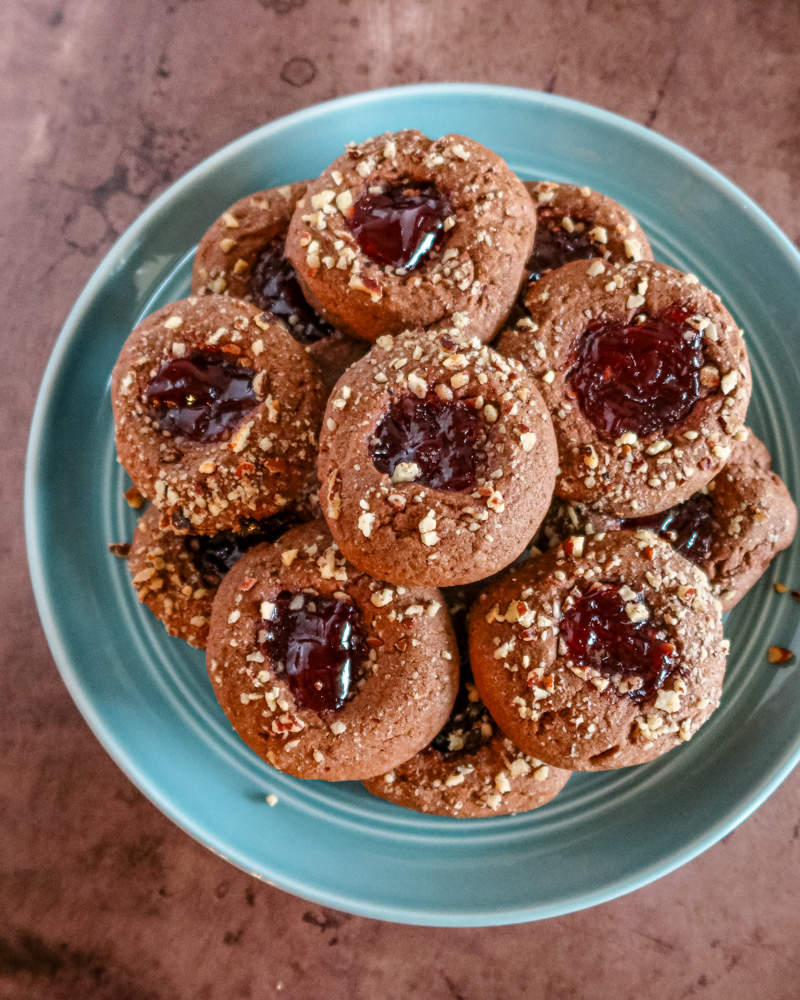 Chocolate raspberry thumbprint cookies on a plate.
