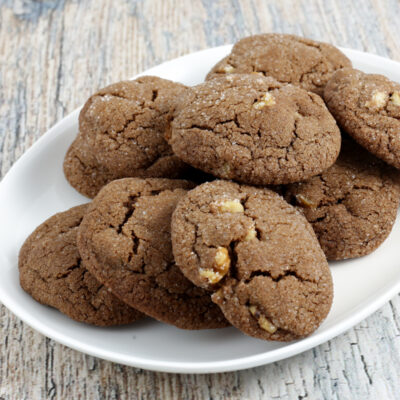 Fudgy chocolate cookies with chopped nuts on white plate.
