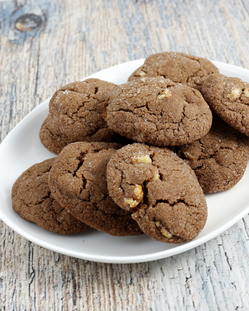 Fudgy chocolate cookies with chopped nuts on white plate.
