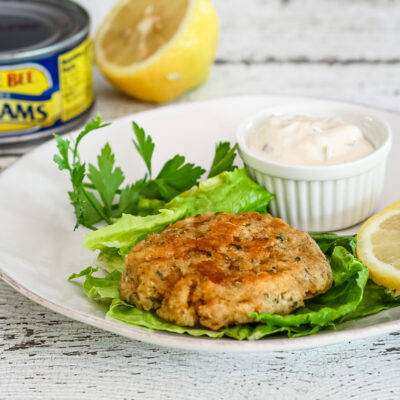 Clam cake on lettuce with tartar sauce and lemon.