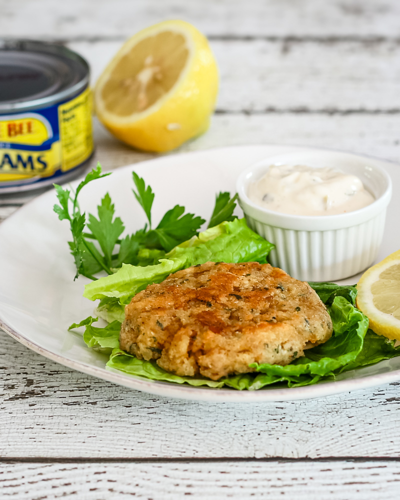 Clam cake on lettuce with tartar sauce and lemon.