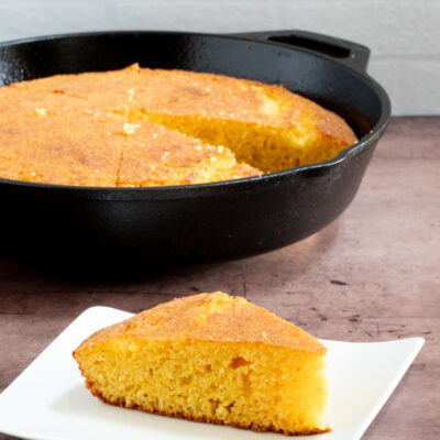 classic american cornbread on a plate with a skillet in the background