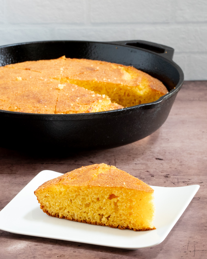 classic american cornbread on a plate with a skillet in the background