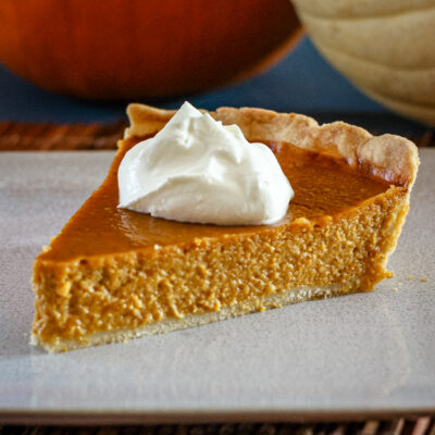 a slice of classic pumpkin pie with whipped cream and a sprinkle of nutmeg