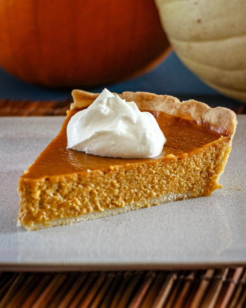 a slice of classic pumpkin pie with whipped cream and a sprinkle of nutmeg