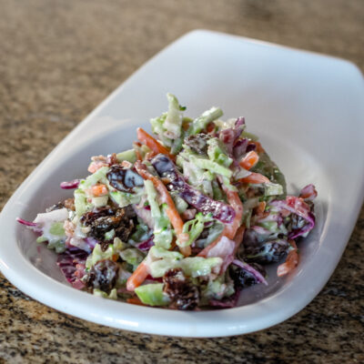 Creamy colorful coleslaw on a small white plate.