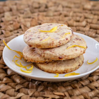 Cranberry orange shortbread cookies on a plate with strips of orange zest.