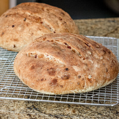 Two round loaves of cranberry walnut yeast bread on a cooling rack.