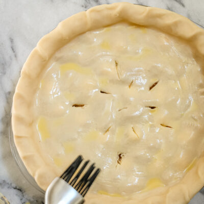 Unbaked pie crust with filling and decorative slits on top.