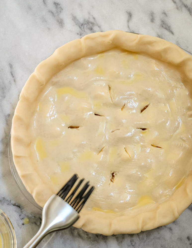 Unbaked pie crust with filling and decorative slits on top.