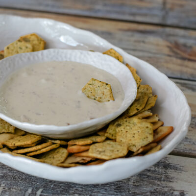 A serving dish with clam dip and crackers.