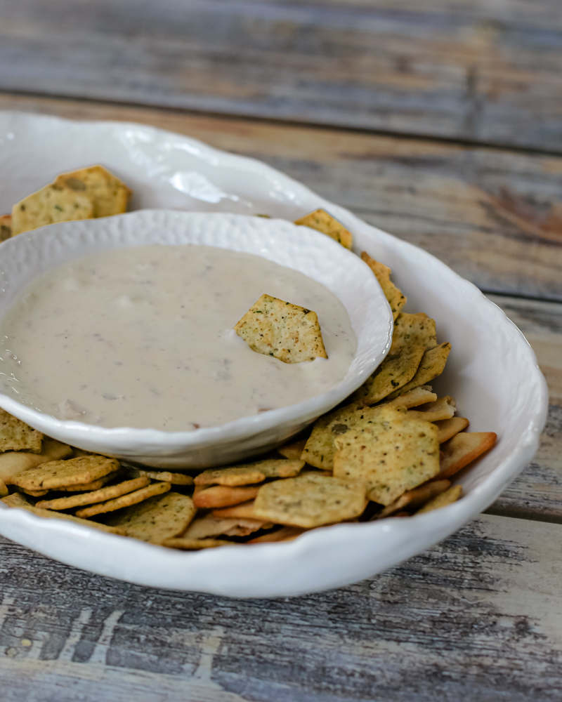 A serving dish with clam dip and crackers.