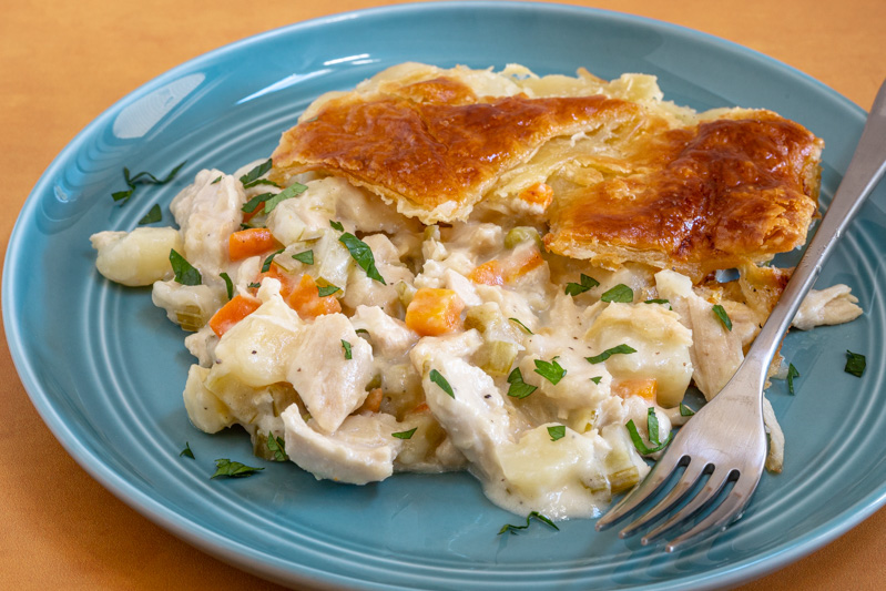 A serving of chicken pot pie with puff pastry topping.