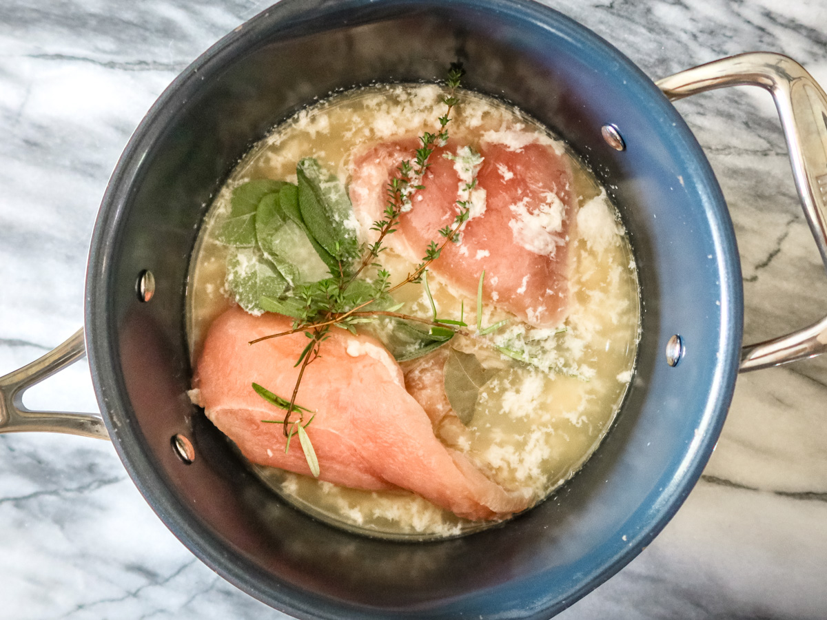 Poaching chicken breasts with broth and herbs.
