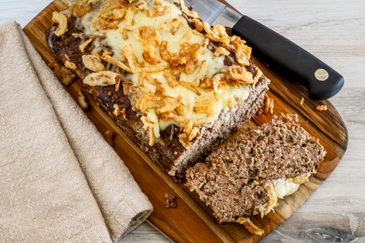 Overhead shot of a sliced French onion meatloaf with Gruyère cheese and fried onion topping.