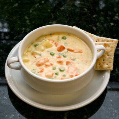 A bowl of salmon chowder with some saltine crackers on the side.