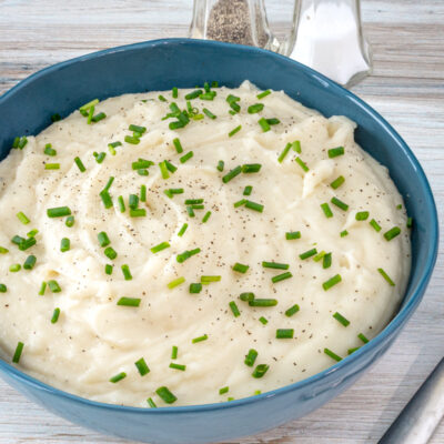 A bowl of Instant Pot pressure cooker mashed potatoes with garnish of herbs.