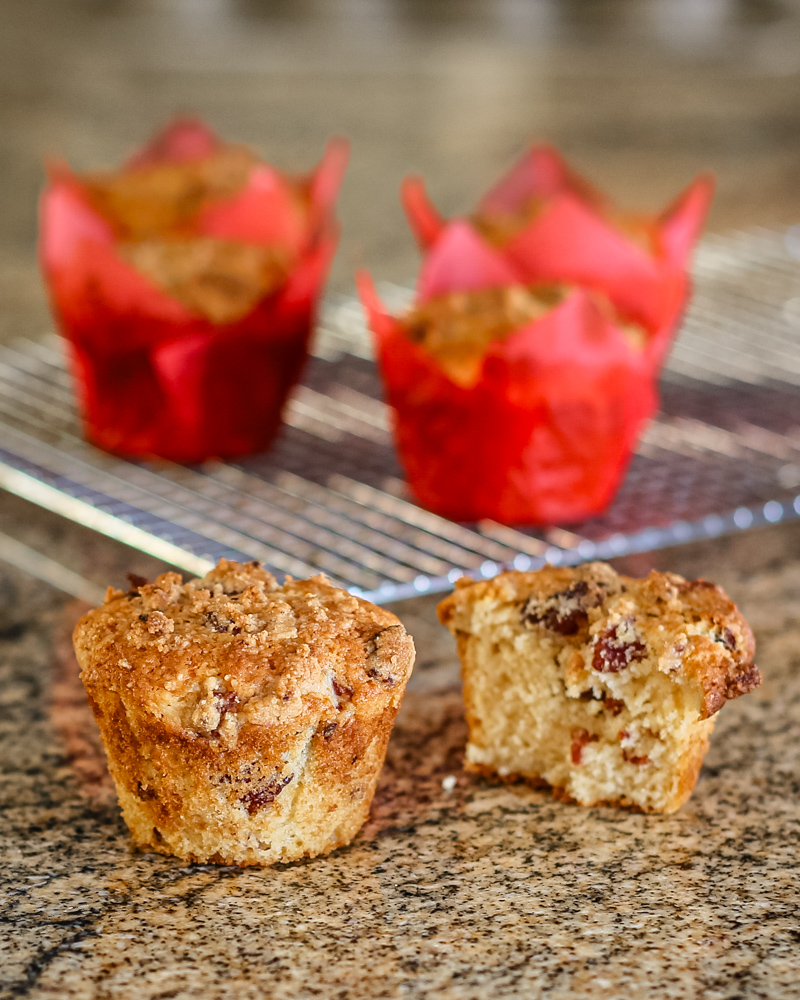 Fresh baked muffins with crumb topping and chocolate chips on a granite countertop.