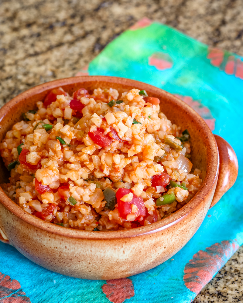 A bowl of Mexican cauliflower rice with tomatoes, green onions, and seasonings.