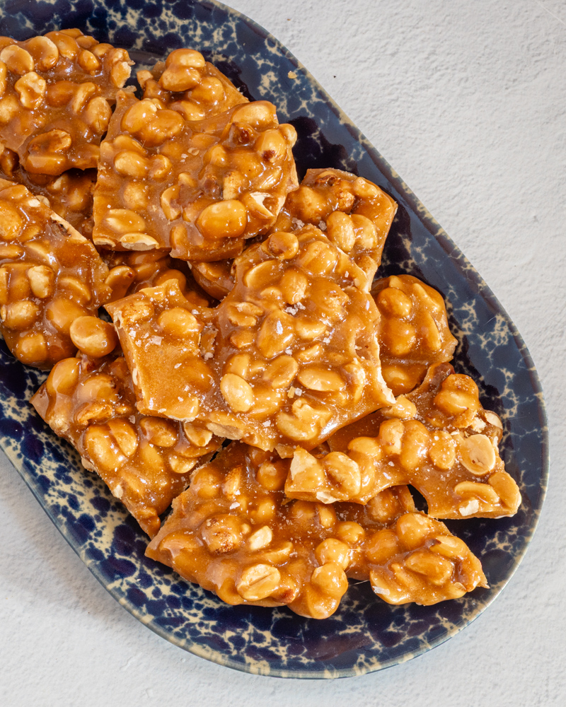 freshly made homemade peanut brittle on a blue pottery tray