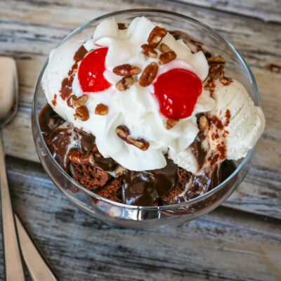 Chocolate sauce on ice cream with whipped cream and cherries