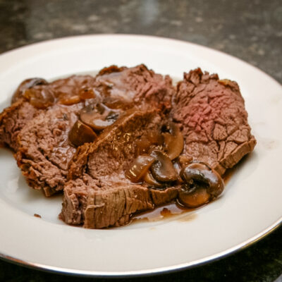 roast beef with gravy on a white plate.