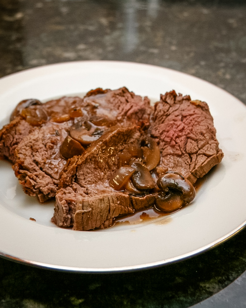 roast beef with gravy on a white plate.
