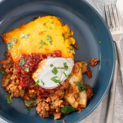 A plate of burrito casserole with sour cream garnish.