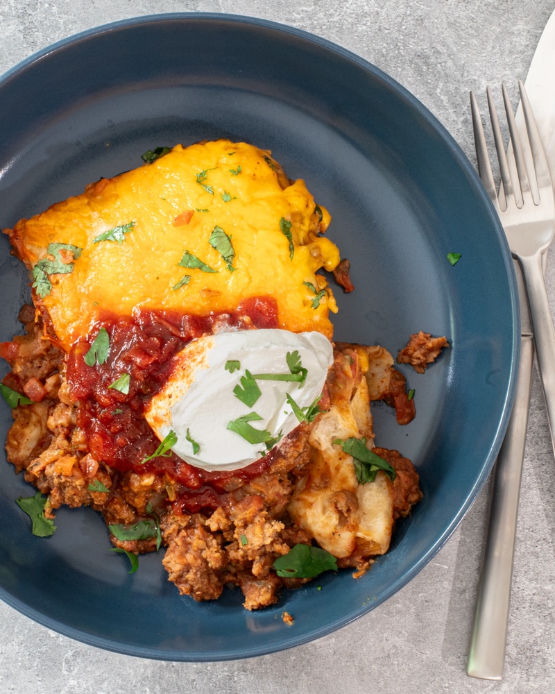 A plate of burrito casserole with sour cream garnish.