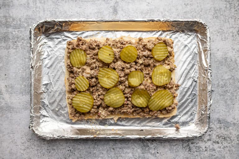 The ground beef mixture and pickles are layered on the Hawaiian rolls.