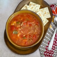 Stuffed pepper soup in a bowl with a spoon and saltines next to it.