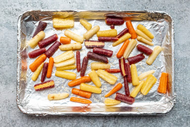 Baby rainbow carrots on a foil-lined baking sheet.