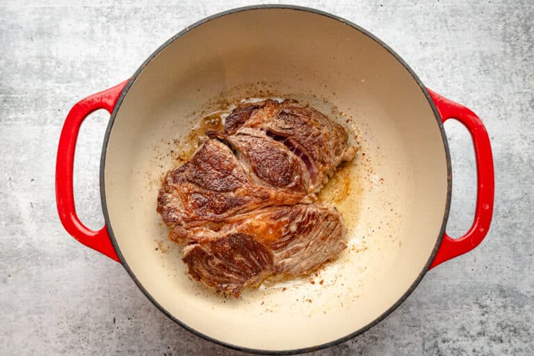 A Dutch oven with browned beef for a Yankee pot roast.