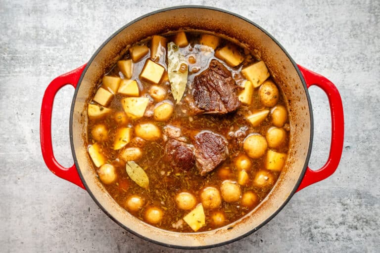 Yankee pot roast in a Dutch oven, surrounded by vegetables.