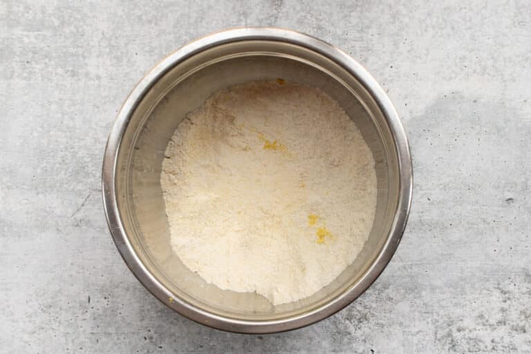 Dry ingredients are combined in a bowl with the lemon zest for blueberry cornmeal muffins.