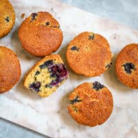 Overhead shot of blueberry corn muffins on a marble slab.