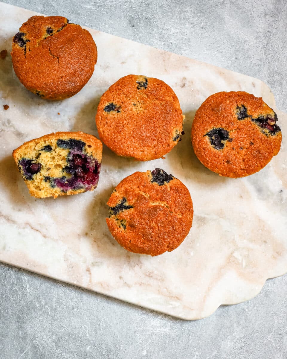Blueberry cornmeal muffins on a marble tray.