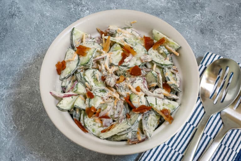 Ranch cucumber salad with bacon and cheddar cheese in a serving bowl.