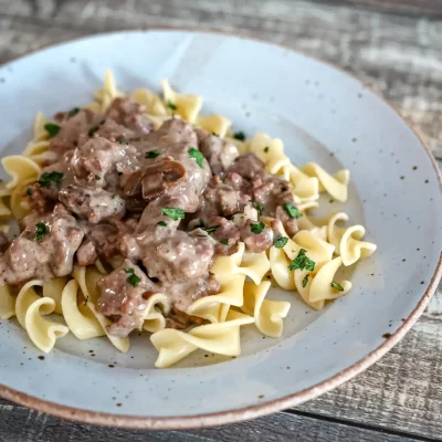 Creamy mushroom sauce over buttered egg noodles, garnished with fresh herbs.